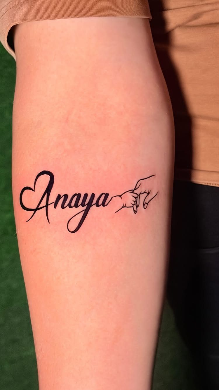 Tattoo of the name Anaya with a heart and holding hands on forearm