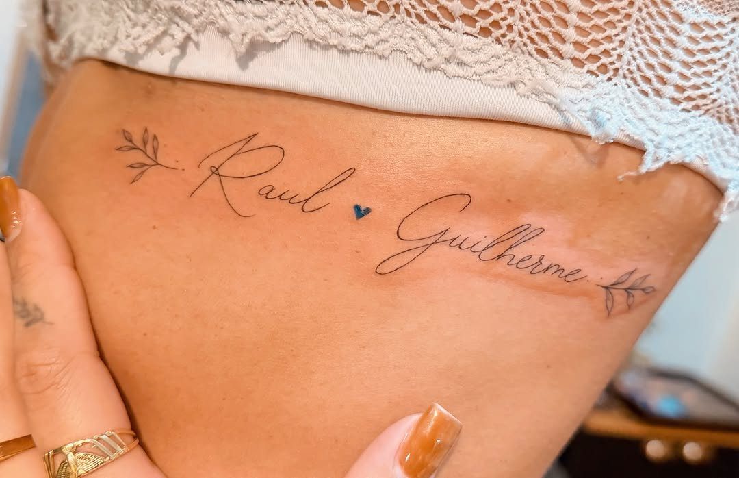 Cursive name tattoos of Raul and Guilherme with a blue heart on a ribcage