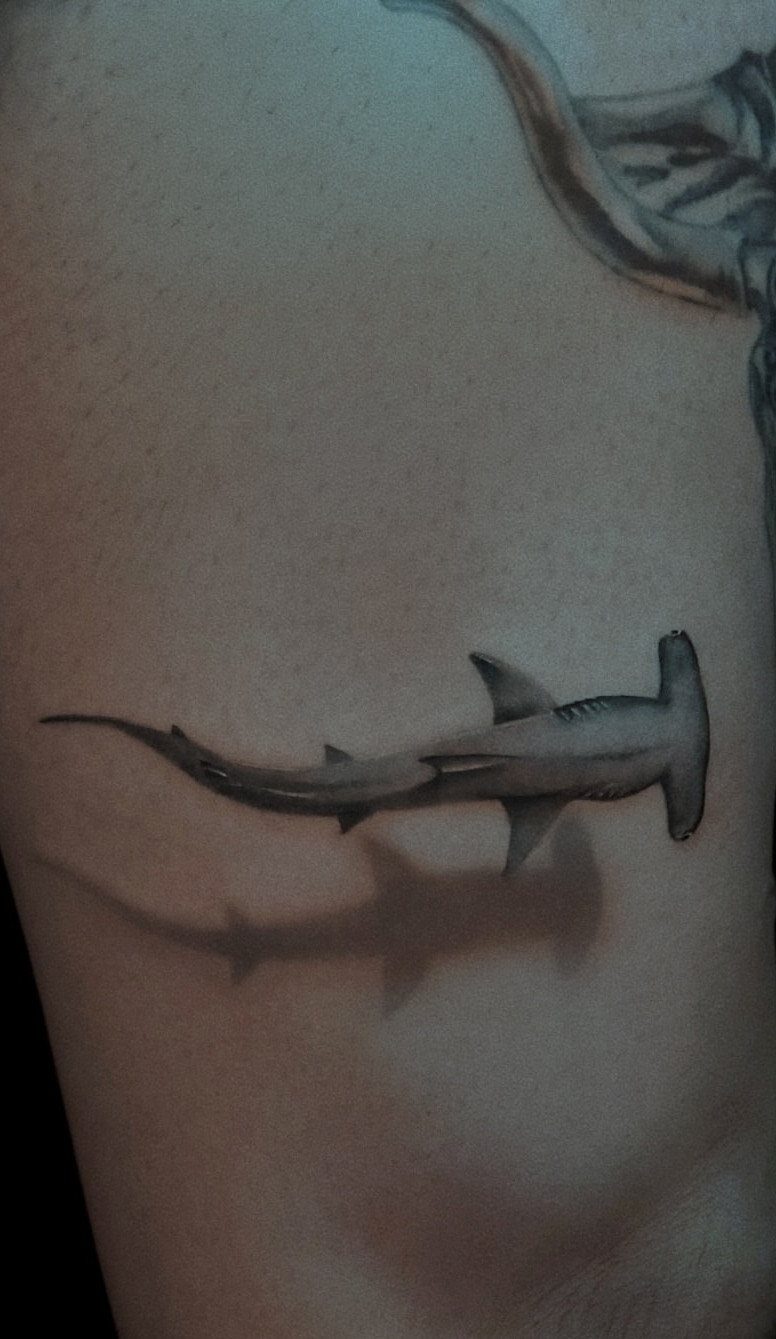 Hammerhead shark tattoo with a 3D shadow effect on a person's skin.