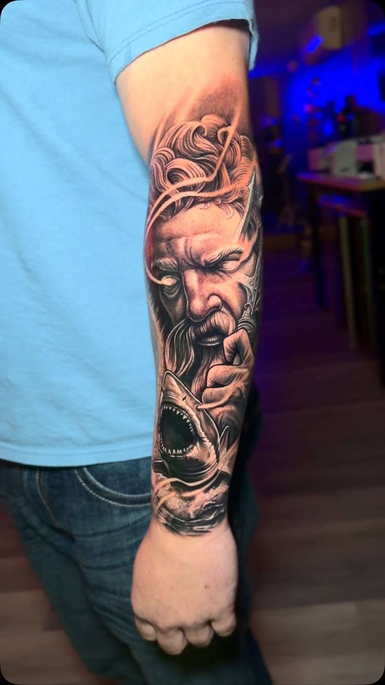 Forearm tattoo of a bearded man and a shark with red highlights.