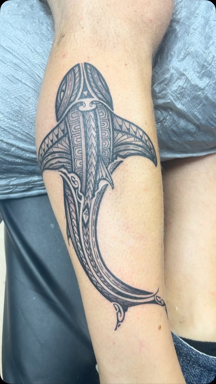 Tribal shark tattoo with geometric patterns on a person's forearm.