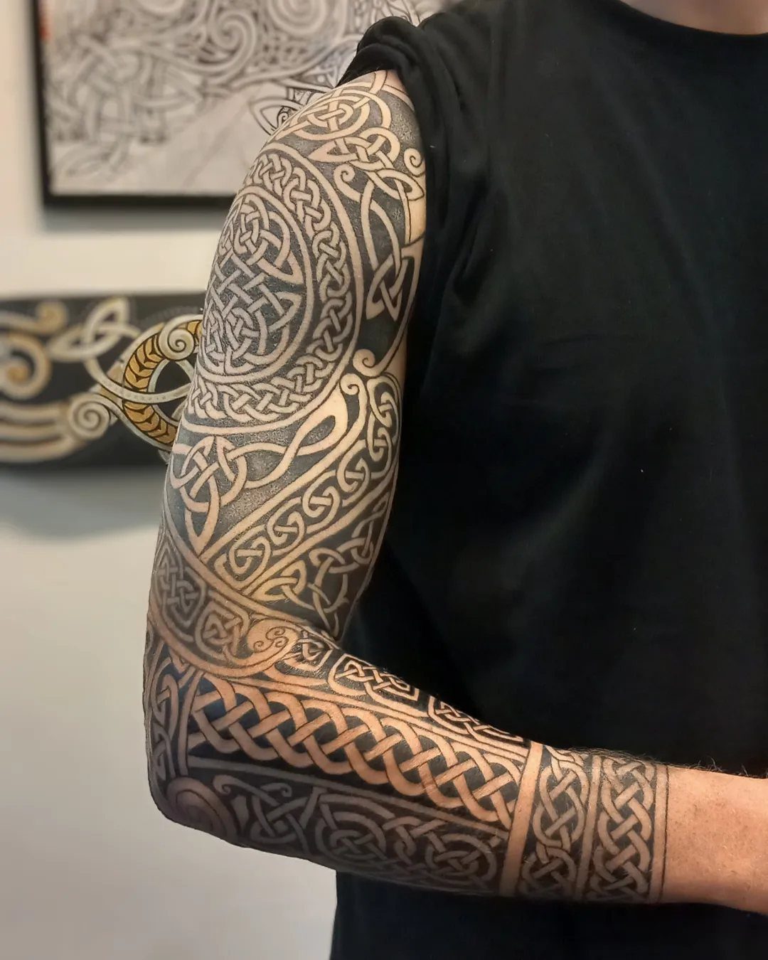 Celtic knotwork sleeve tattoo covering a person's entire arm in black ink