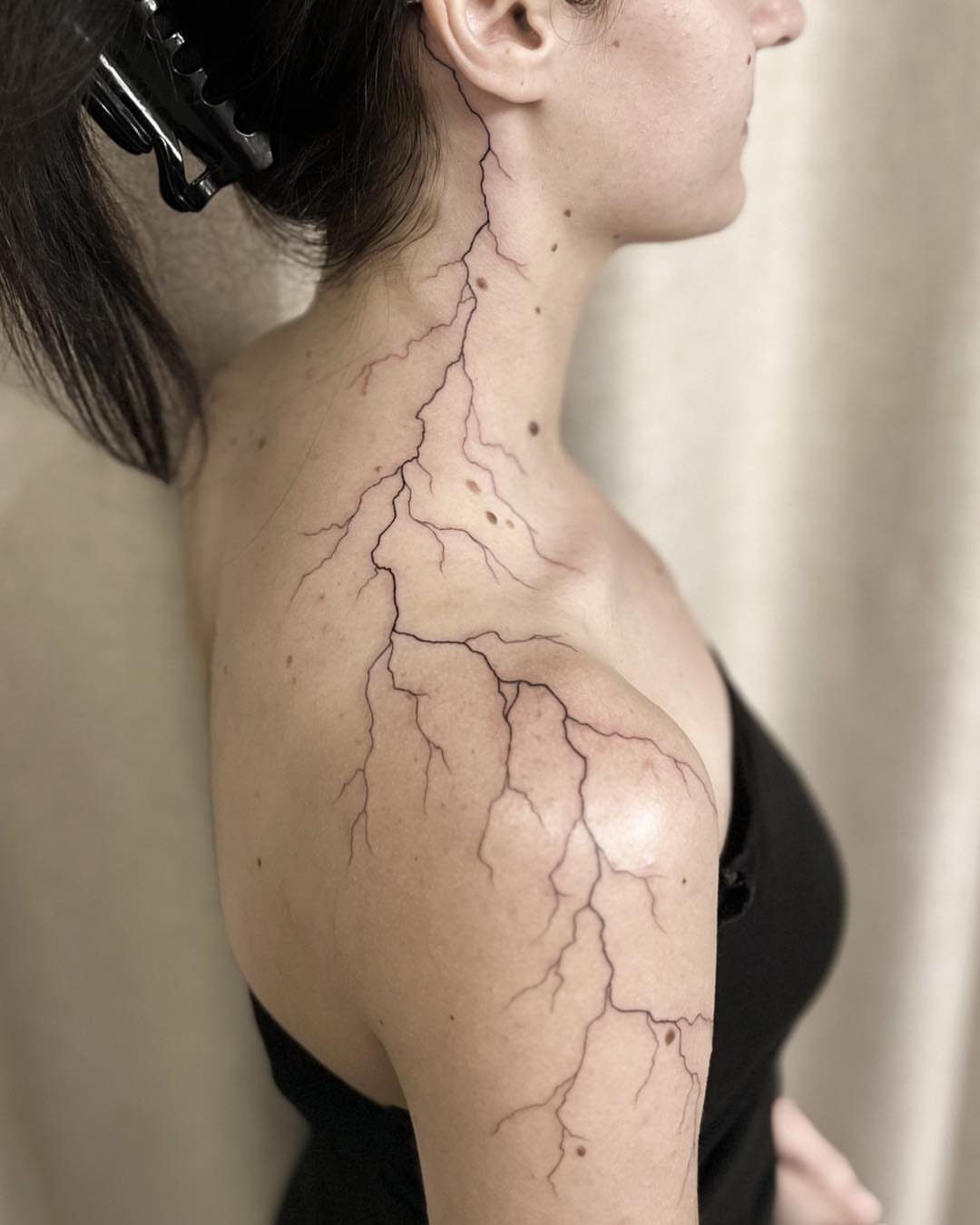 Lightning bolt tattoo extending from the neck down to the shoulder of a person.