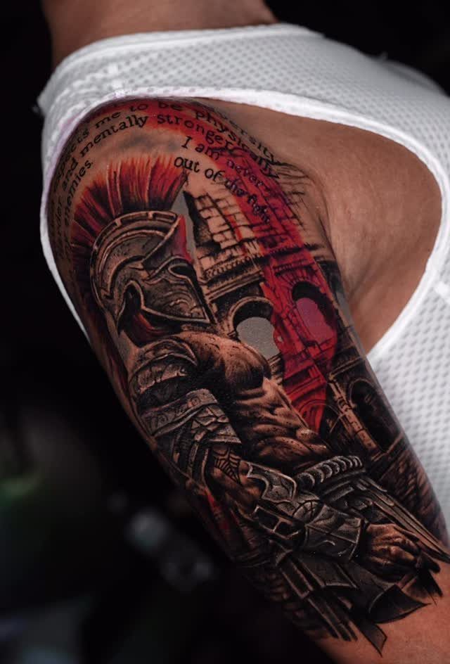 Spartan warrior tattoo with red plumed helmet and Roman architecture on an arm.