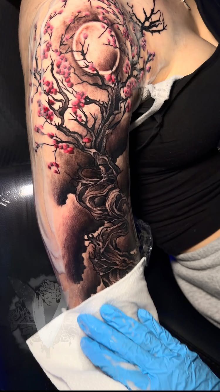 Tree tattoo with pink blossoms and a moon on a person's arm