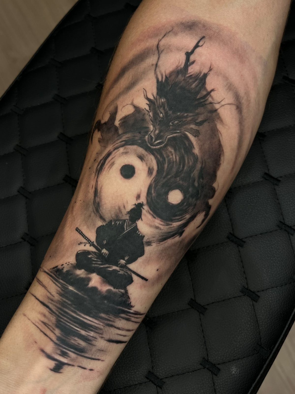 Yin and Yang tattoo on arm featuring a dragon and meditating samurai.