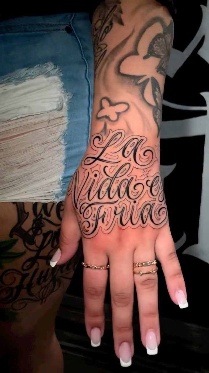 Ornate Chicano style tattoo on a hand reading La Vida es Fria