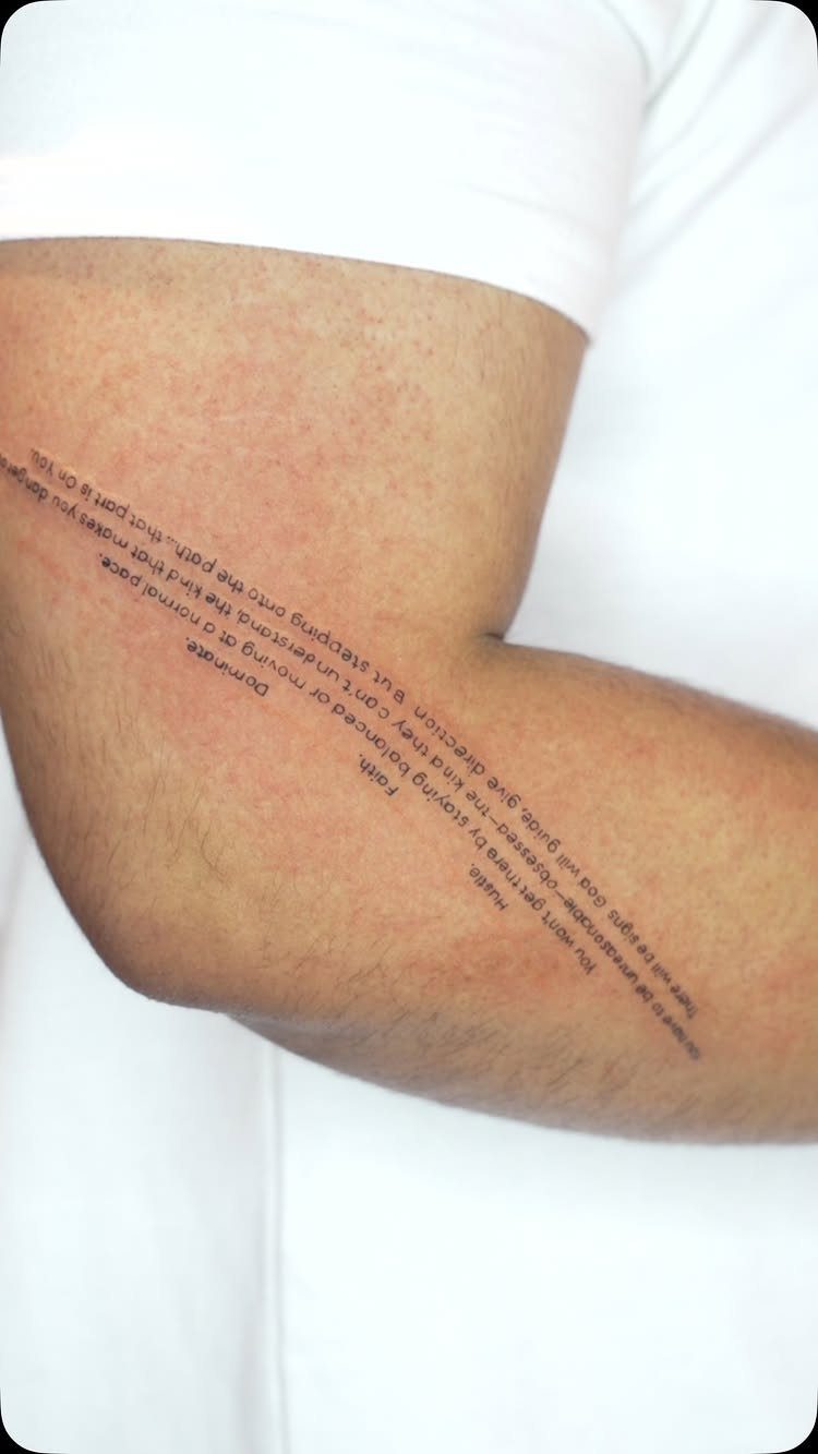 Tattooed text in a clean serif font running along a person's forearm