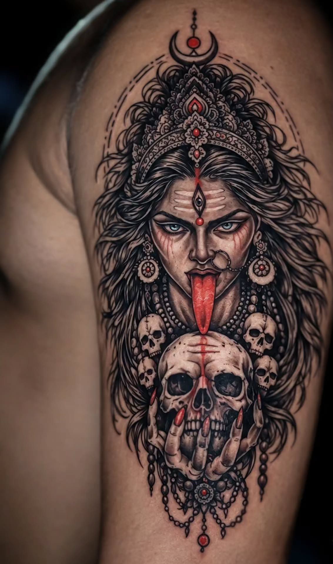 Maa Kali tattoo on an arm featuring a crown, tongue, and skull.