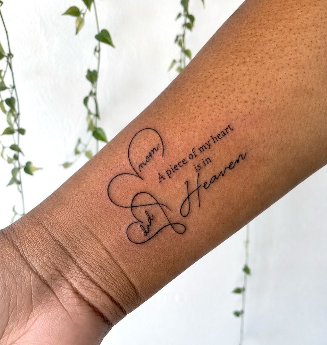 Heart tattoo on a forearm with text about mom and dad in heaven