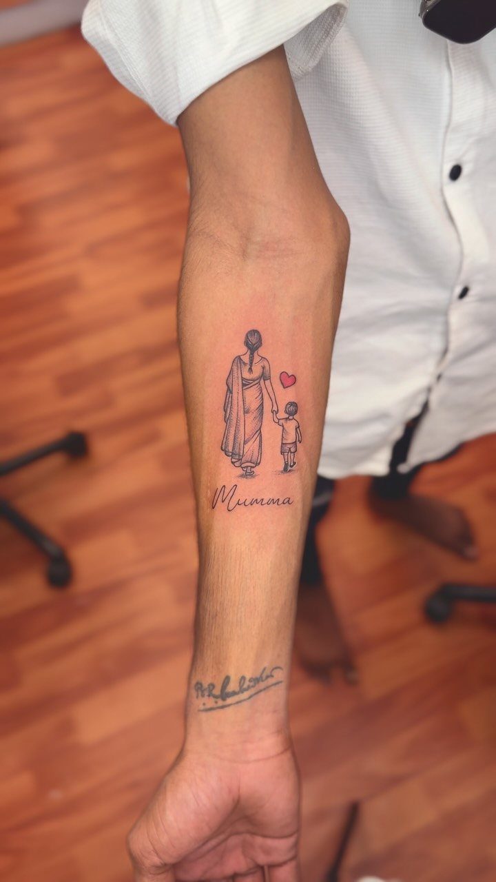 Forearm tattoo of a mother in a sari holding a child's hand
