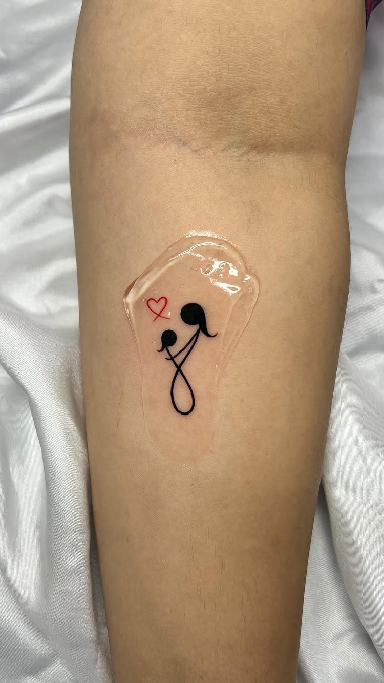 Stylized black ink mother and child tattoo with a red heart on forearm