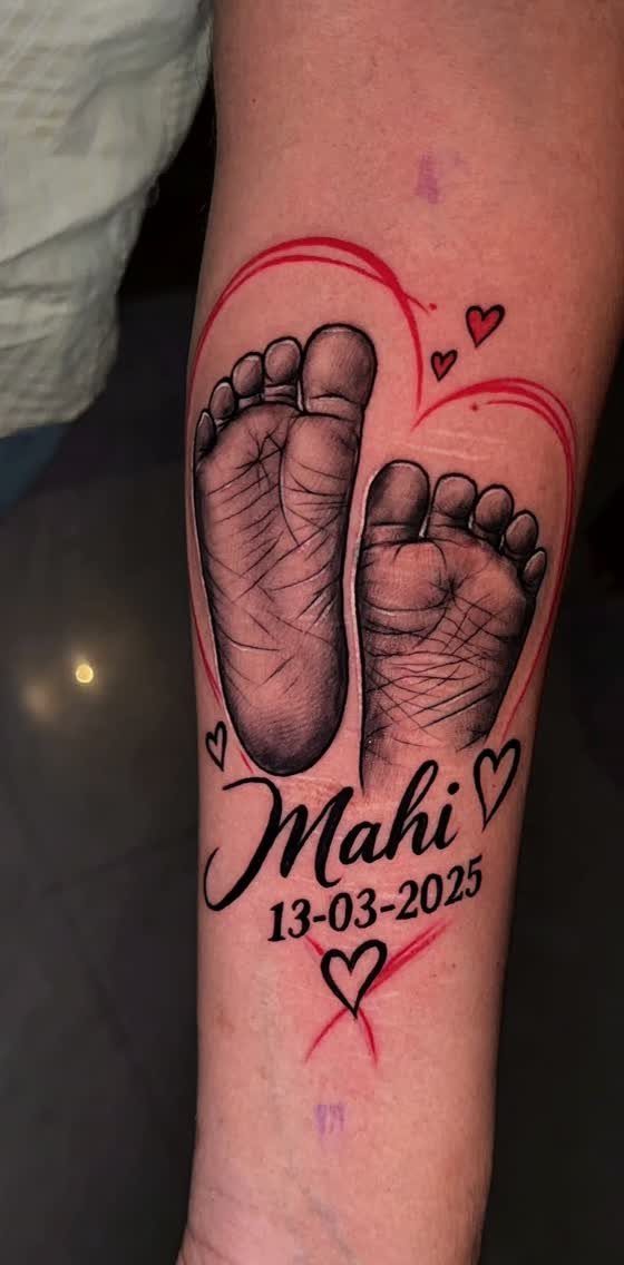 Baby footprint tattoo with the name Mahi and date 13-03-2025 on a forearm.