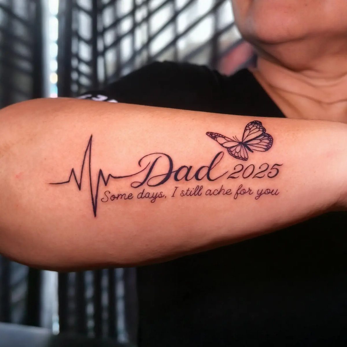 Forearm tattoo with heartbeat line, Dad, 2025, a butterfly, and cursive text.