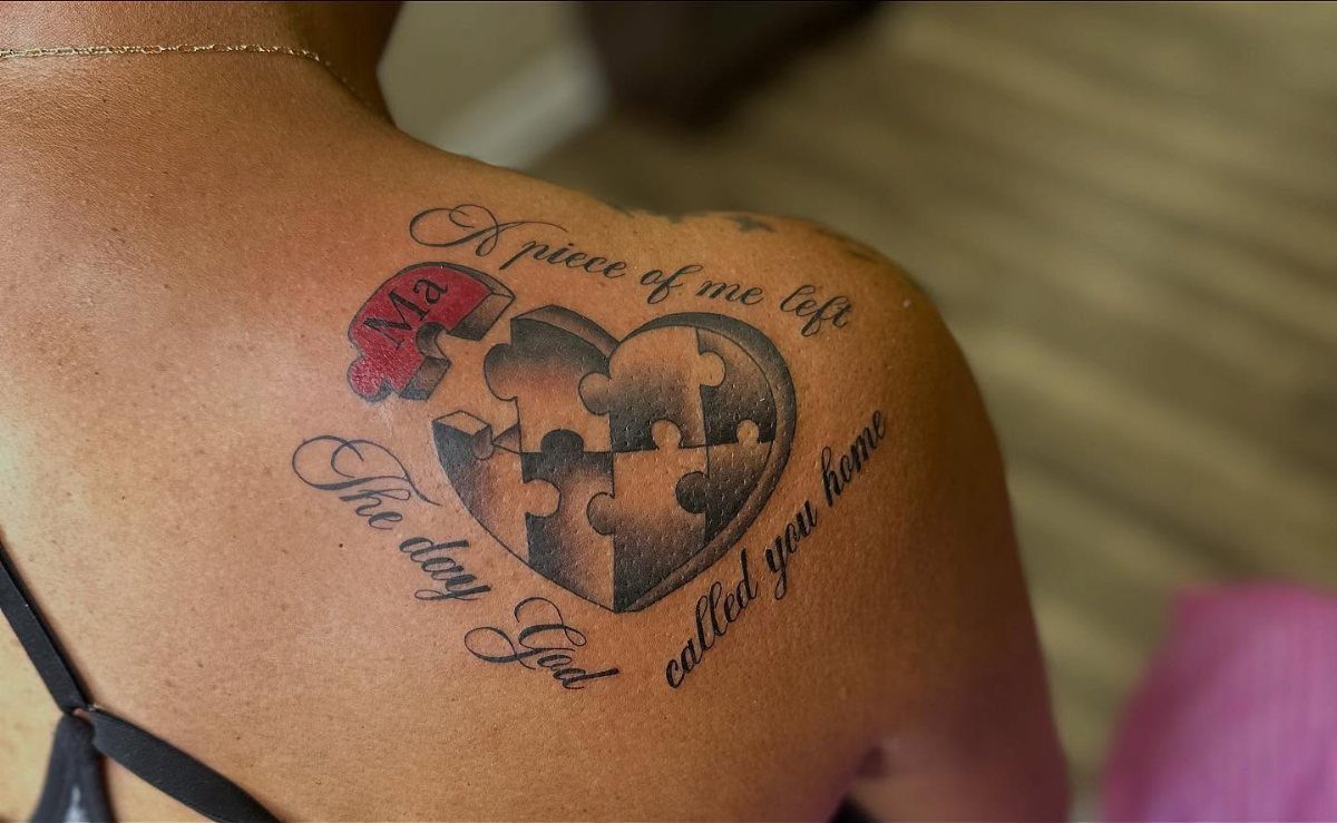 Heart-shaped puzzle tattoo on a shoulder with memorial text and a red puzzle piece.