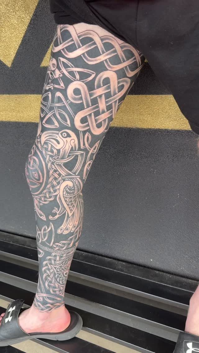 Celtic knotwork tattoo sleeve covering a person's entire leg in black and grey ink