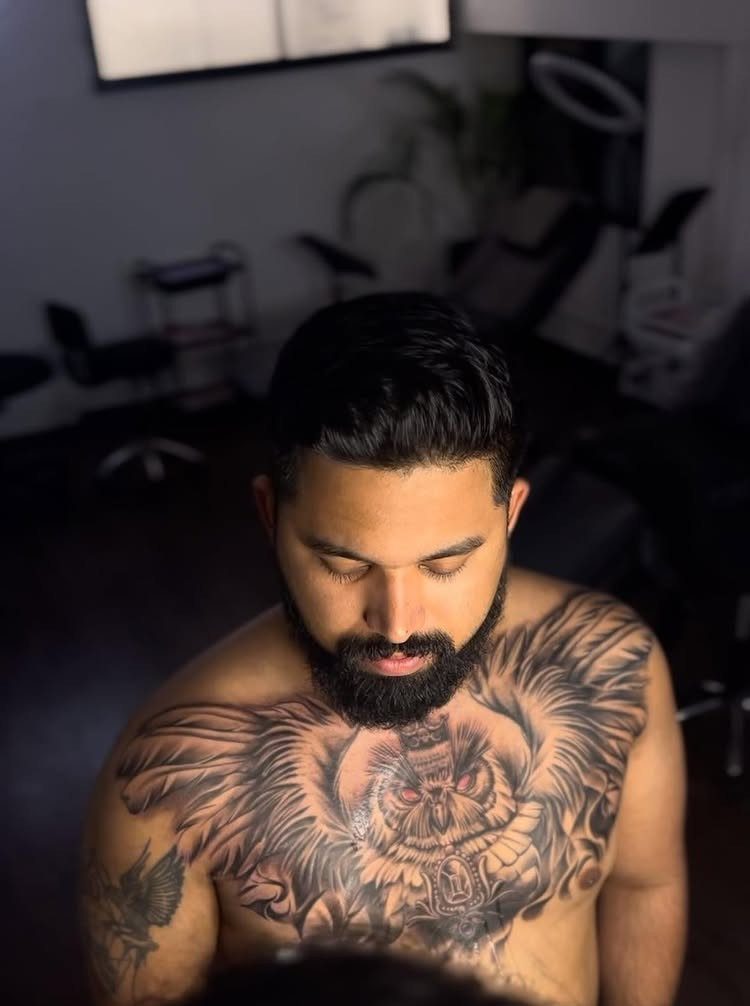 Man with a large, detailed owl tattoo spread across his chest and collarbone.
