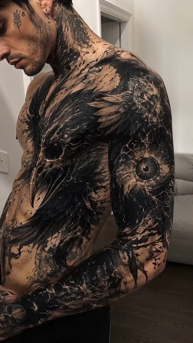 Man with a large black raven and skull tattoo across his chest and arm