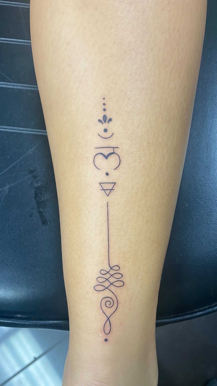 Unalome tattoo on a forearm with a spiral, knot, and geometric symbols.
