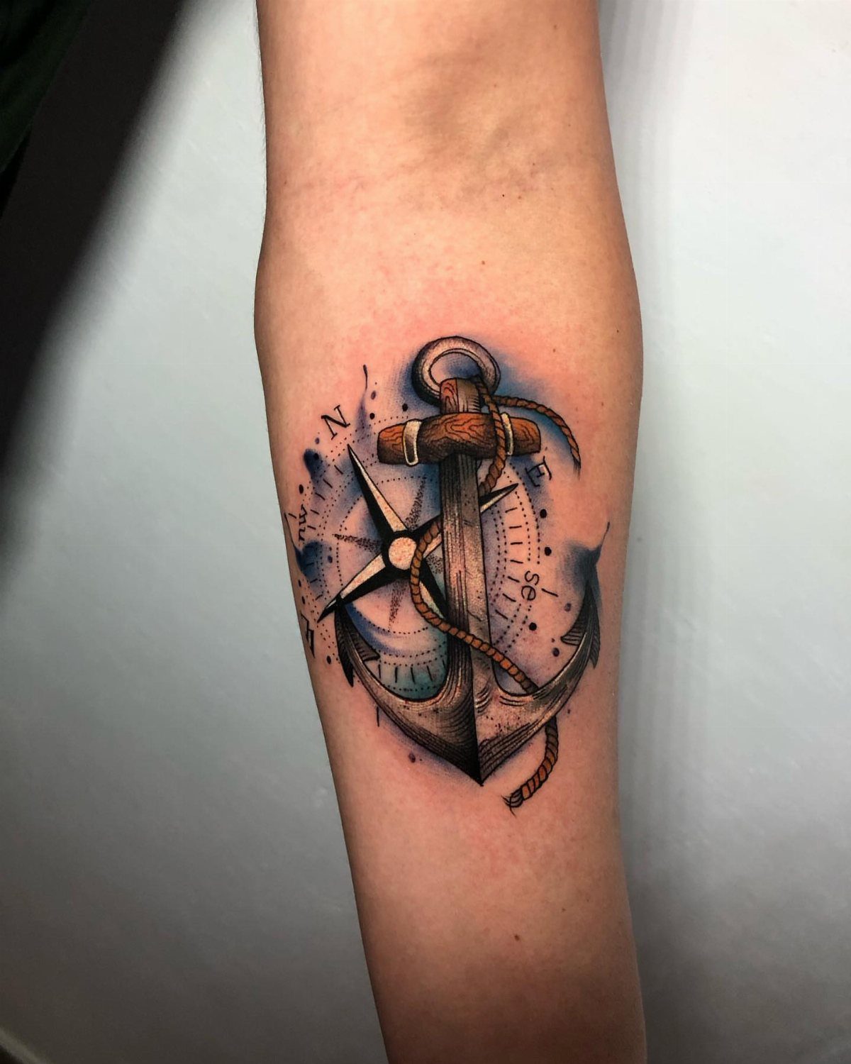 Anchor tattoo with rope and compass rose on a person's forearm.