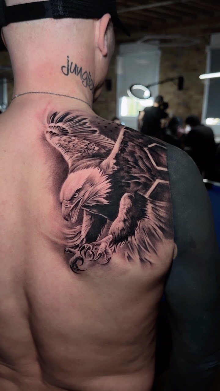 Detailed black and grey eagle tattoo on a man's upper back and shoulder.