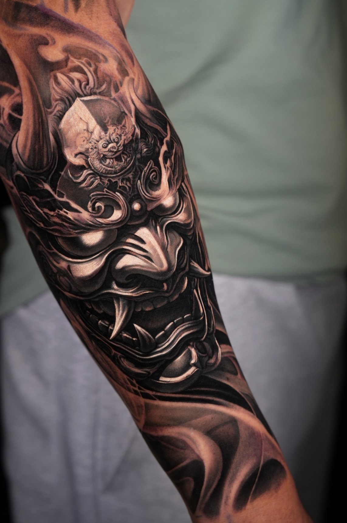 Japanese Hannya mask tattoo in black and grey ink on a man's forearm