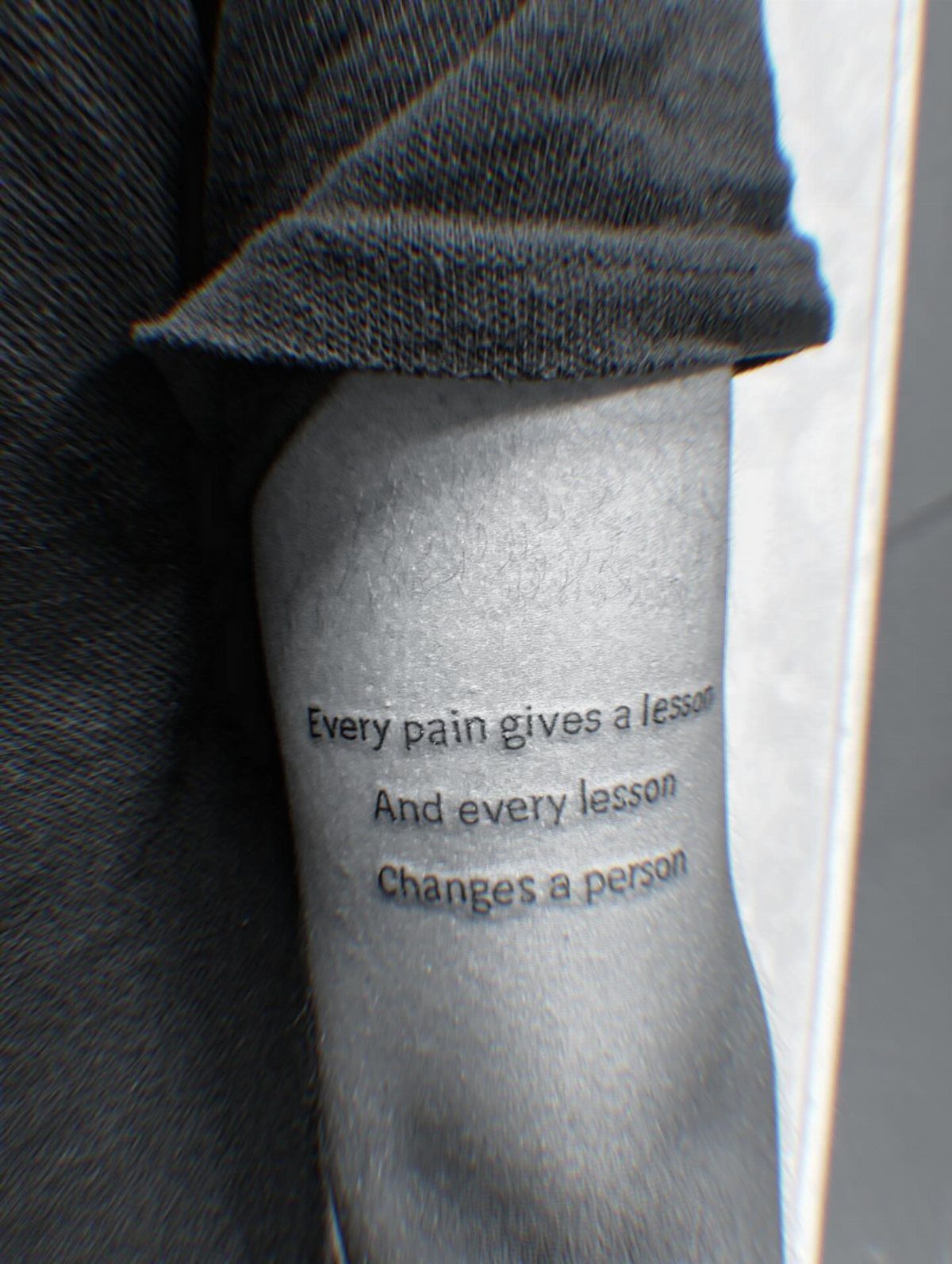 Tattoo on an arm with the quote Every pain gives a lesson