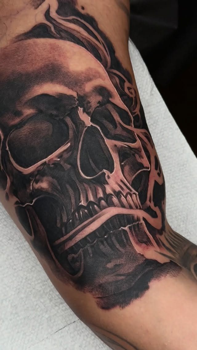 Detailed black and grey skull tattoo on a person's forearm with realistic shading.