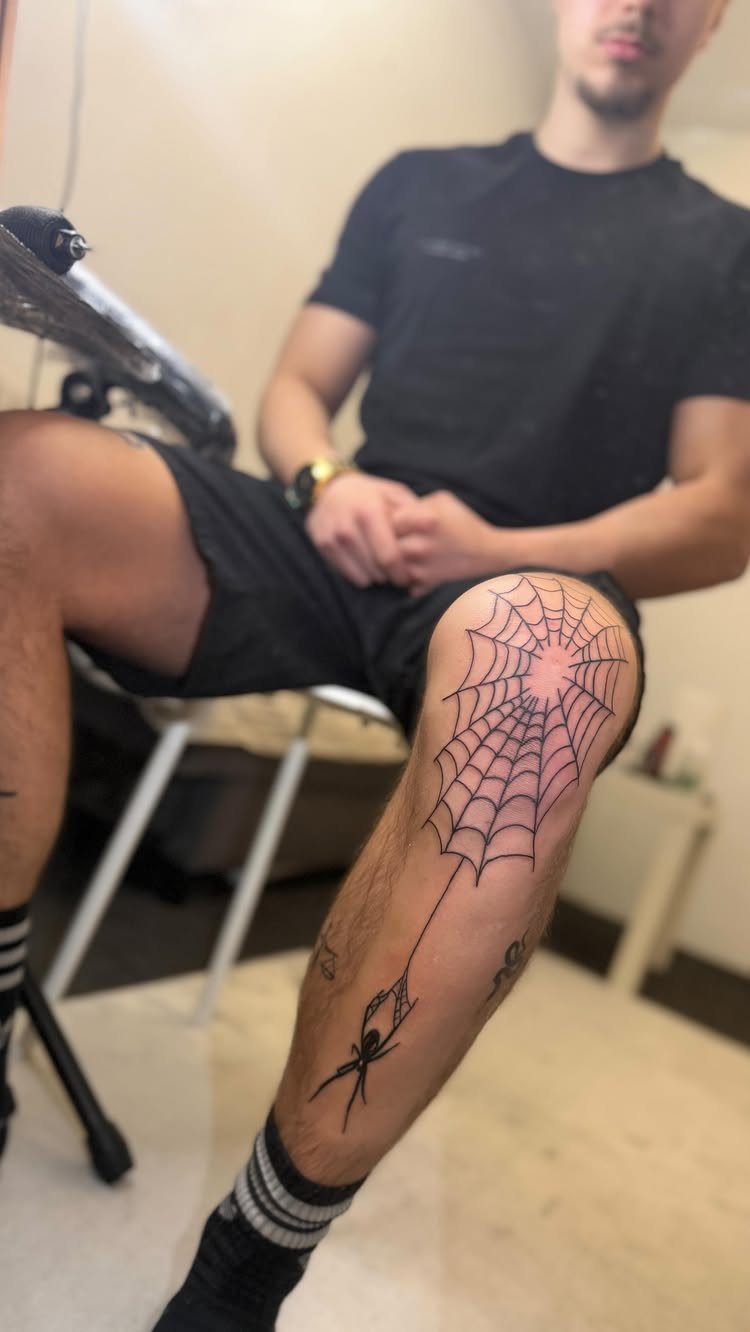 Spider web and spider tattoo on a man's knee and lower leg