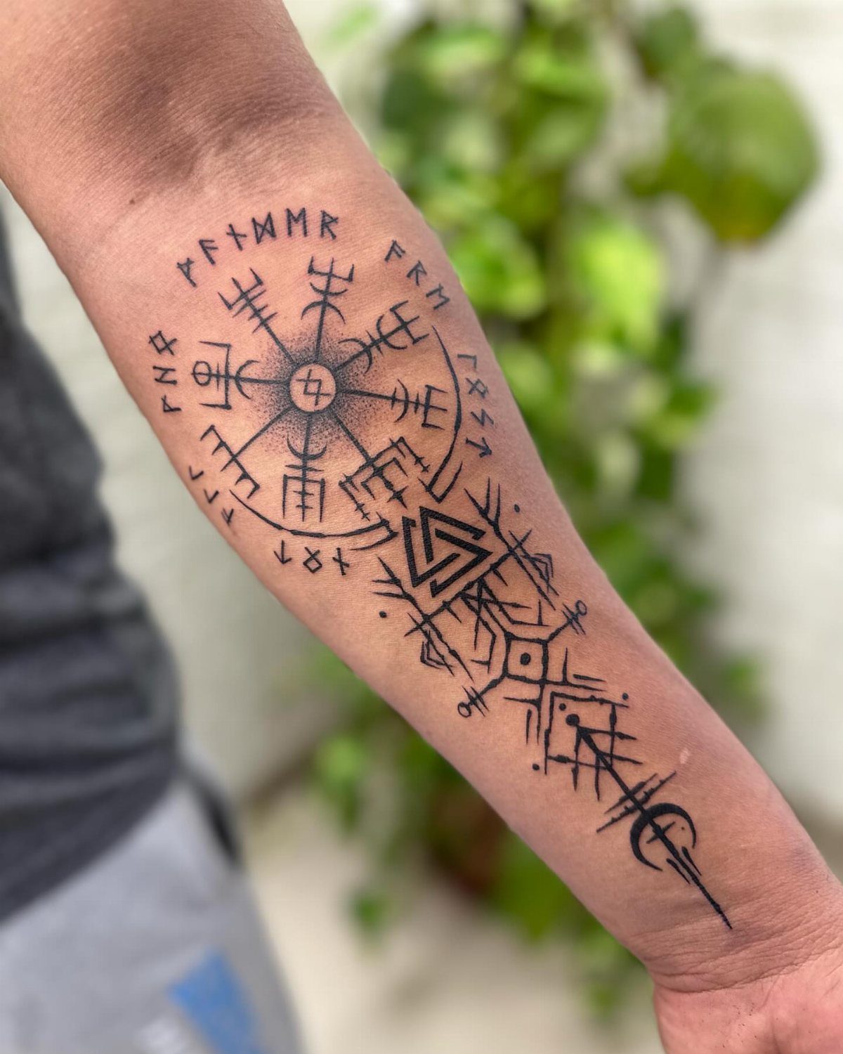 Norse tattoo on forearm featuring a Vegvisir compass and a Valknut symbol.