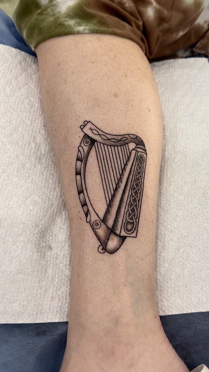 Celtic harp tattoo with knotwork details on a person's lower leg