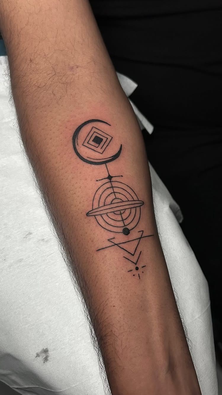 Geometric black ink tattoo on a forearm featuring a moon, circles, and triangle.