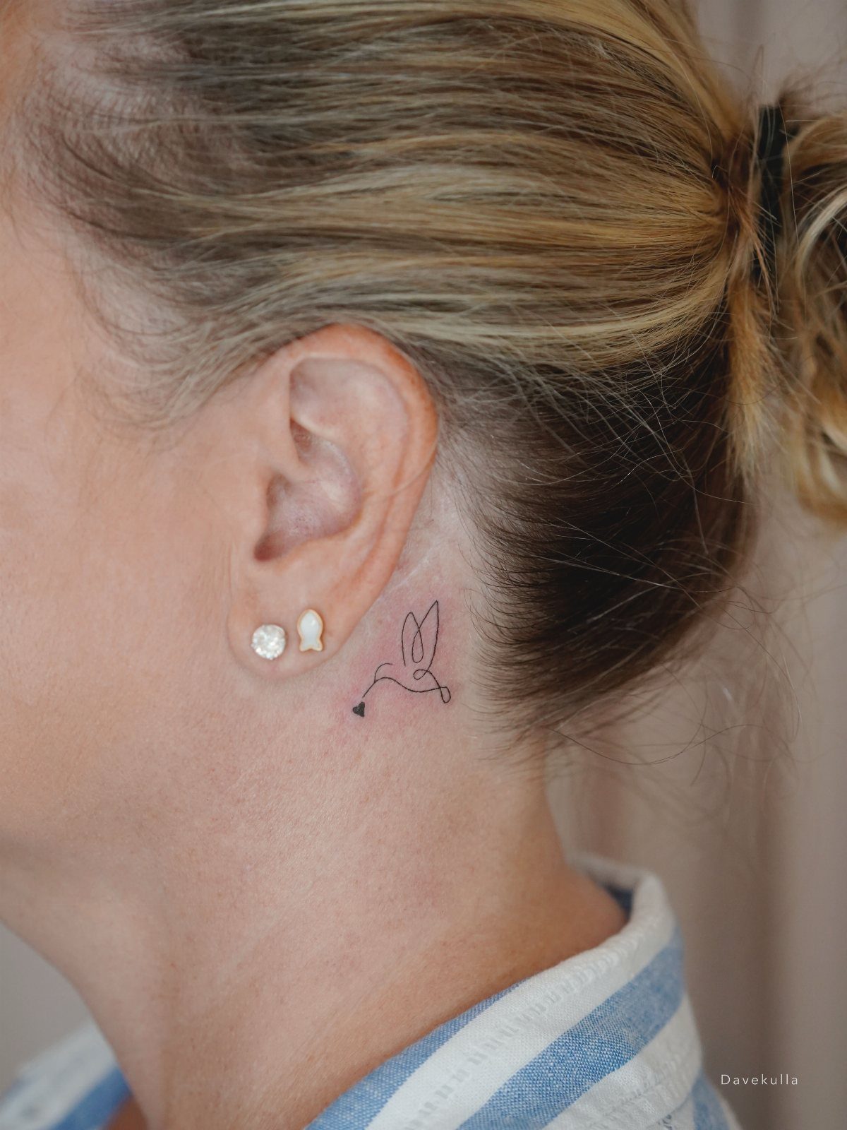 Small minimalist hummingbird tattoo on the side of a person's neck.