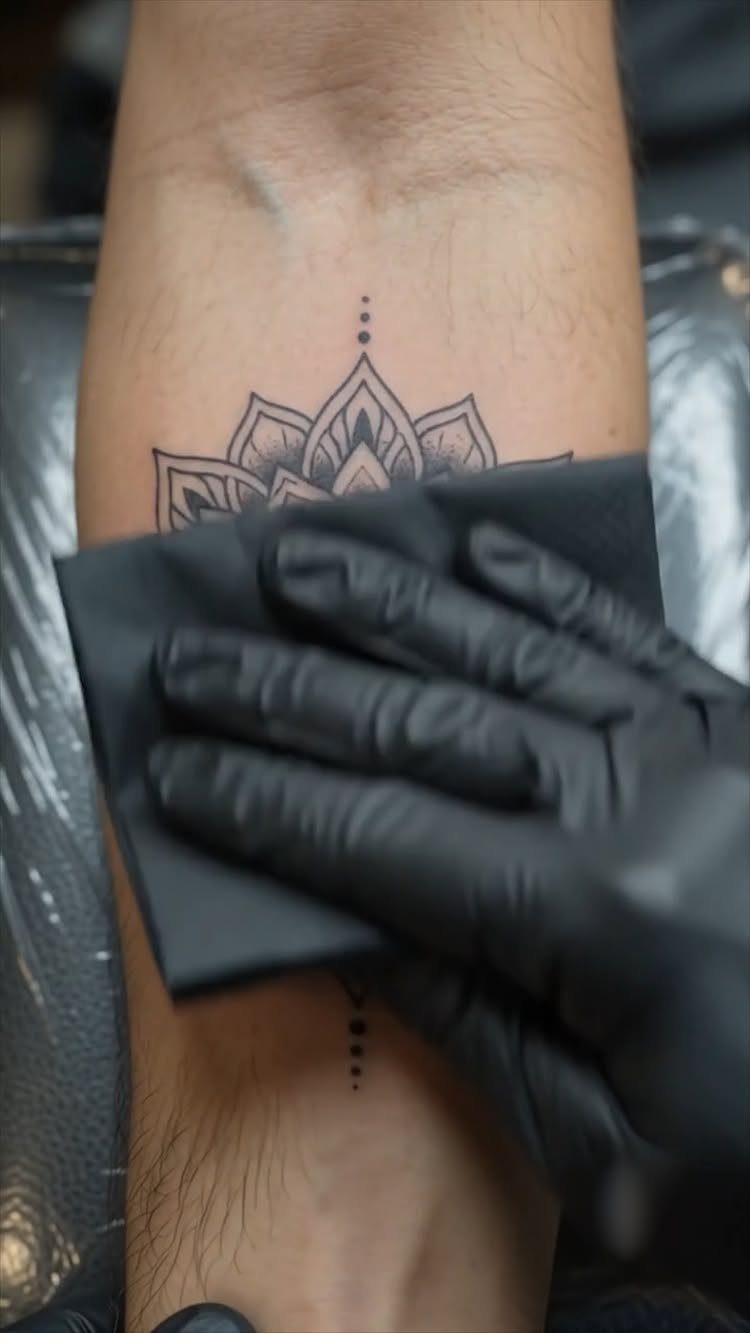 Mandala tattoo on a forearm being wiped clean by a gloved hand
