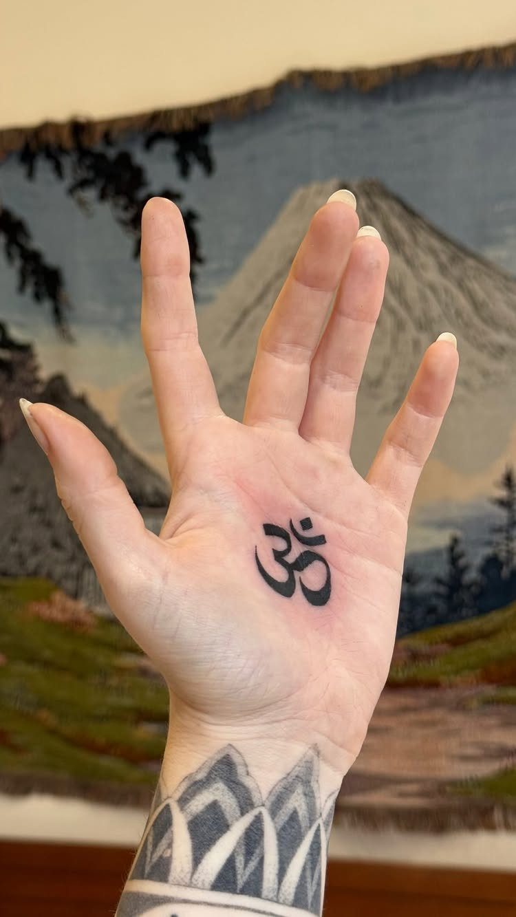 Om symbol tattoo on the palm of a hand with geometric wrist art