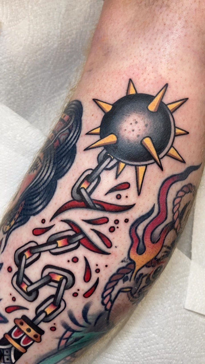 Spiked mace and chain tattoo in traditional American style on a forearm.