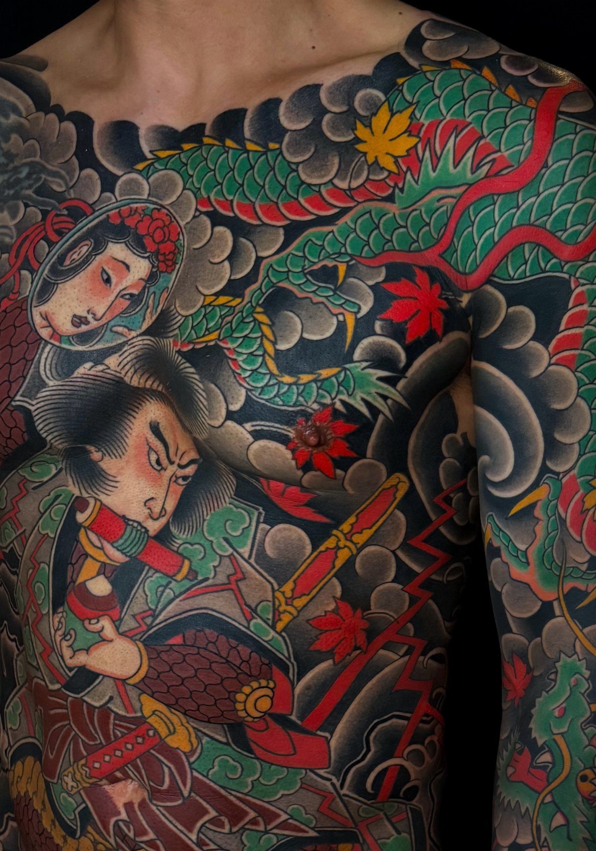 Traditional Japanese tattoo on a torso featuring a samurai and a green dragon.