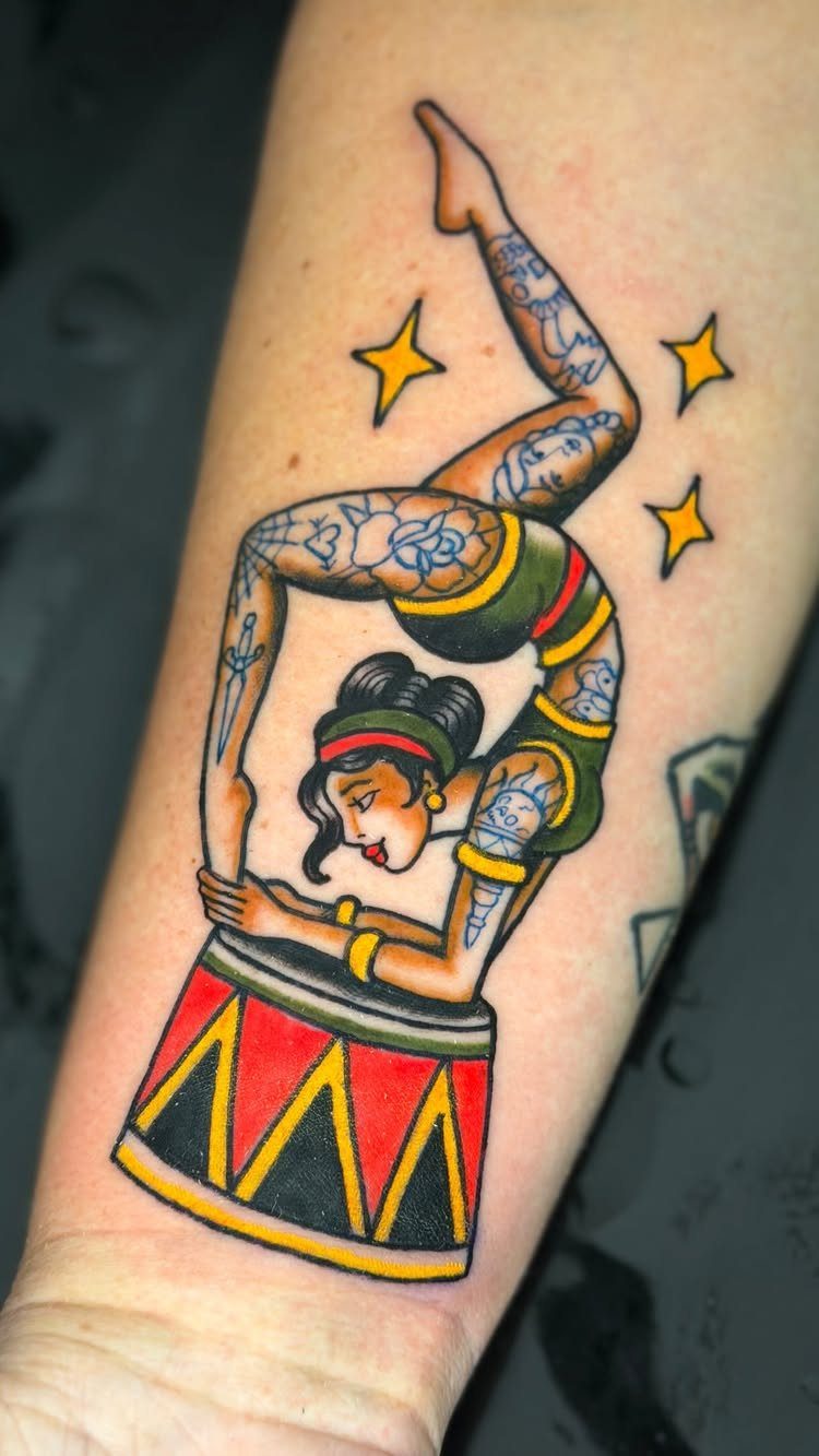 Traditional tattoo of a pin-up woman performing a backbend over a colorful drum.
