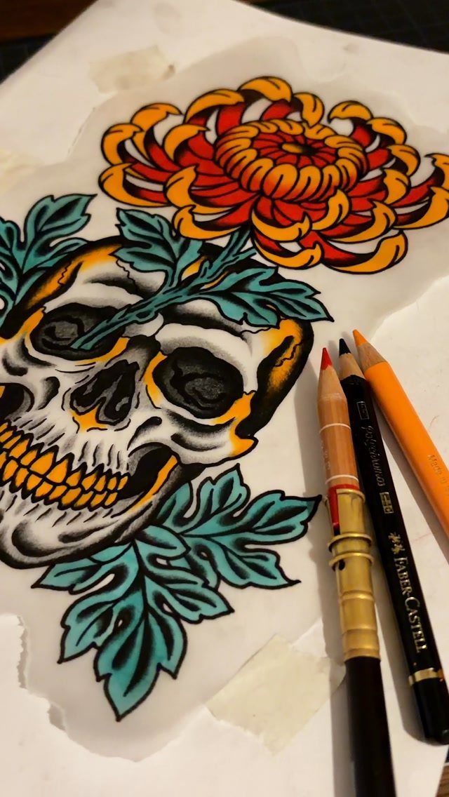 Traditional tattoo design of a skull with an orange chrysanthemum and teal leaves.