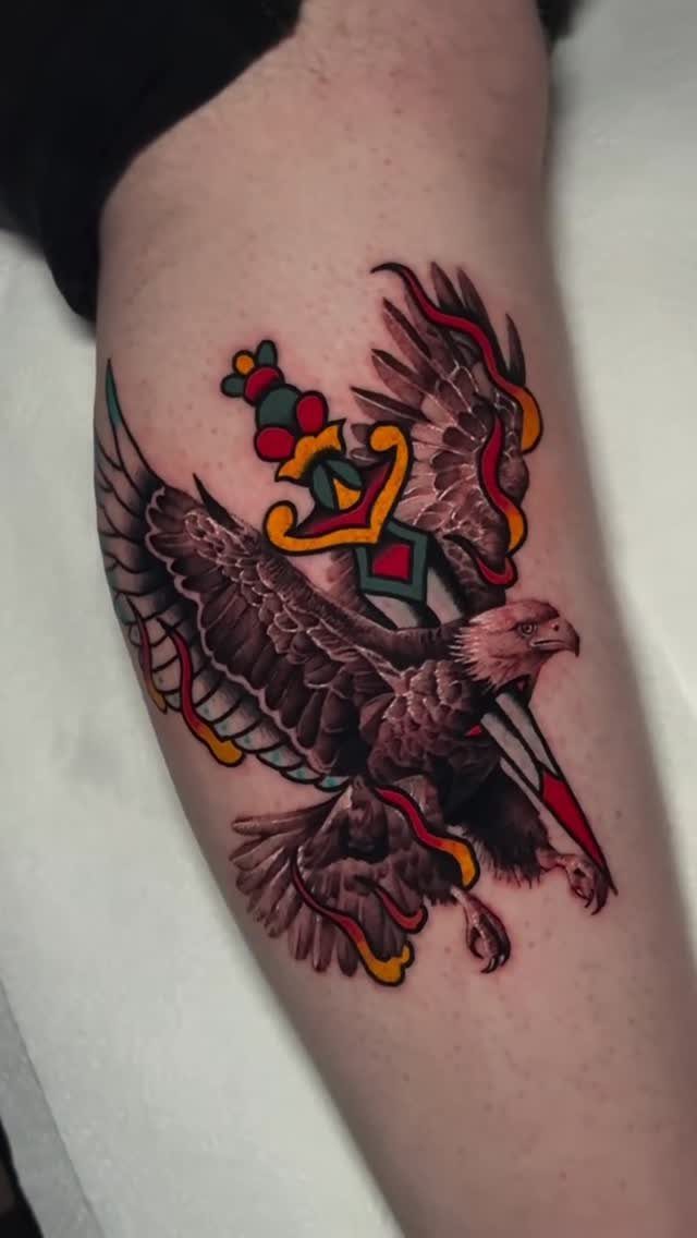 Traditional style tattoo of an eagle and sword on a person's forearm