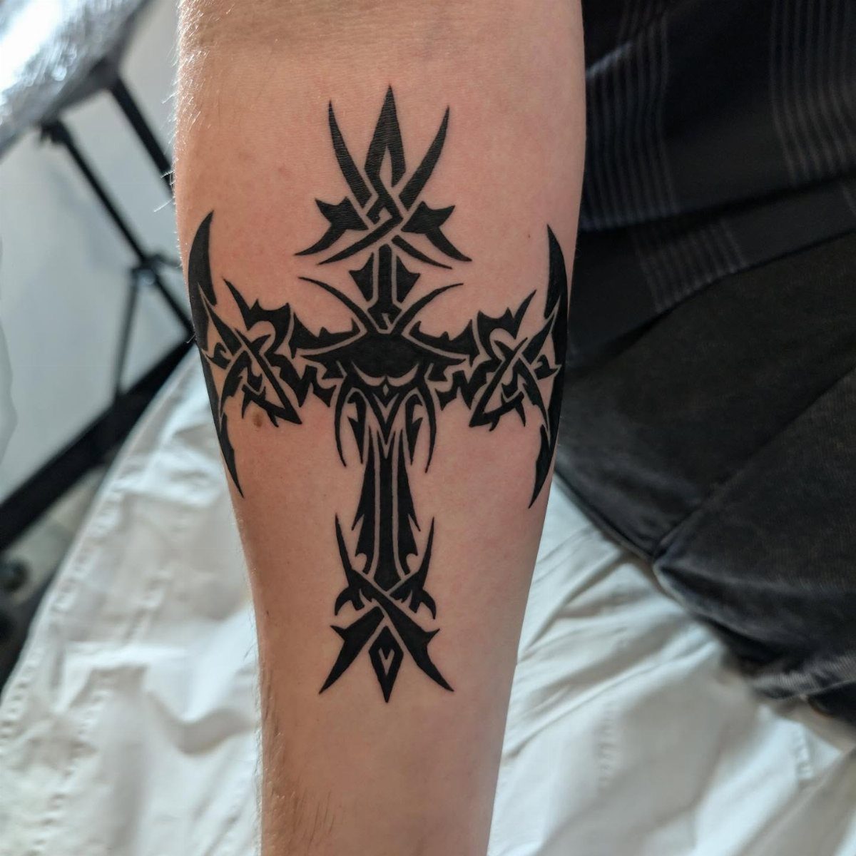 Tribal cross tattoo with bold black ink lines on a person's forearm