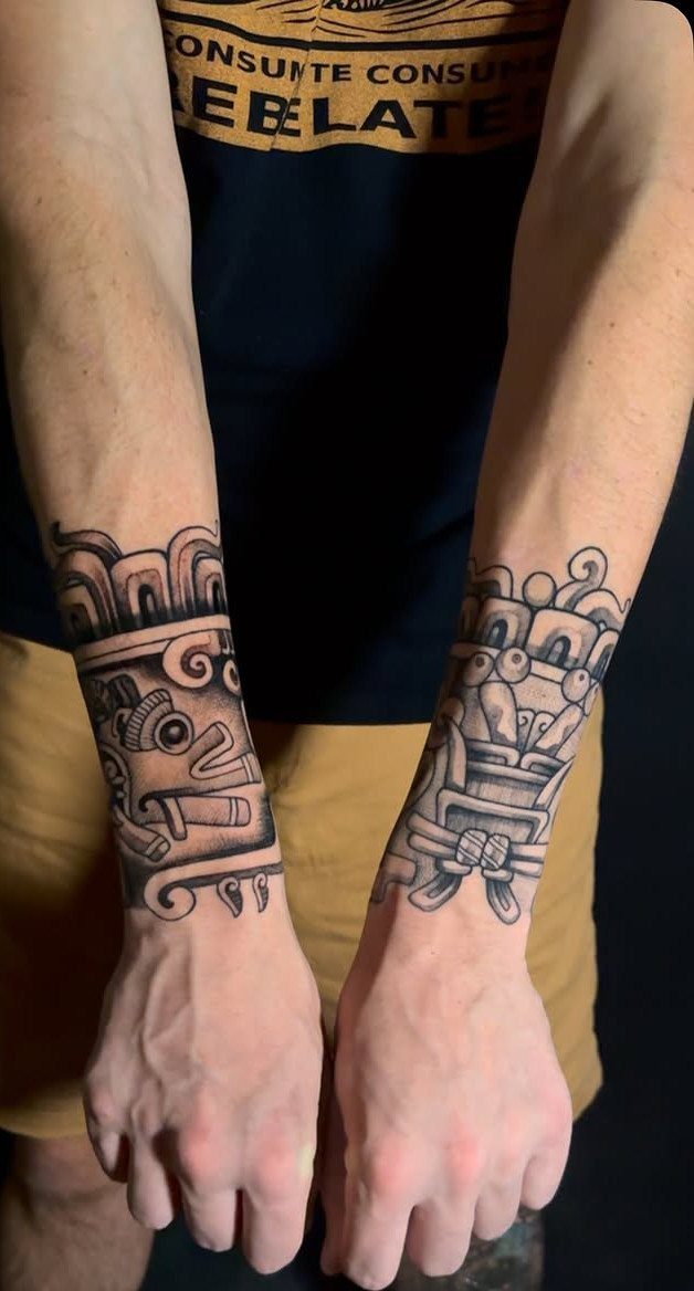 Black ink Aztec tribal tattoos on a person's wrists and lower forearms.