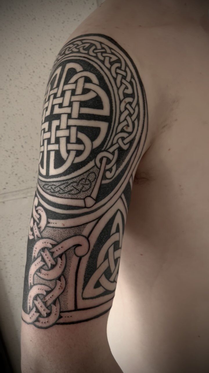 Celtic knotwork tattoo on an upper arm with intricate interlocking black ink patterns.