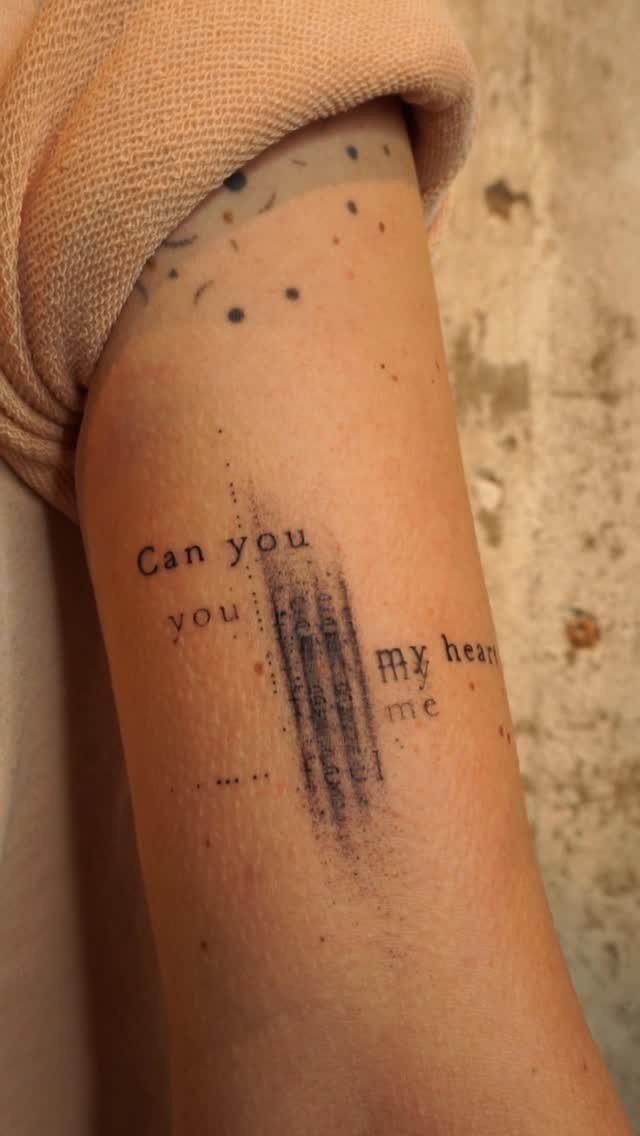 Forearm tattoo with typewriter font text and a vertical ink smudge effect.