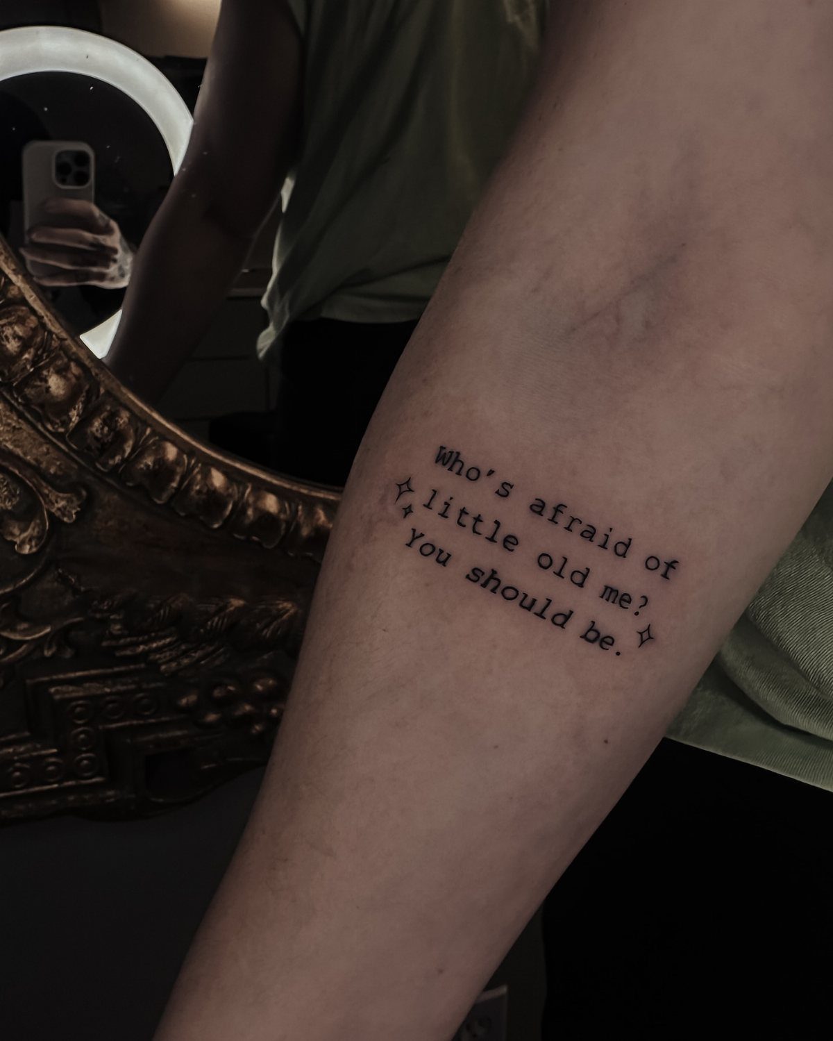 Forearm tattoo with typewriter font text and small stars on a person's skin.