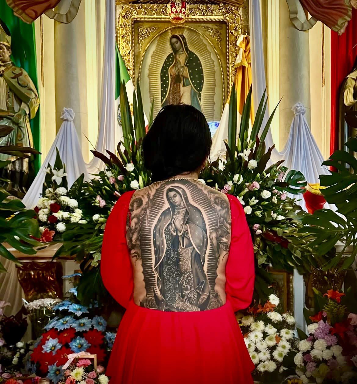Woman with a large Virgin Mary tattoo on her back facing a church altar