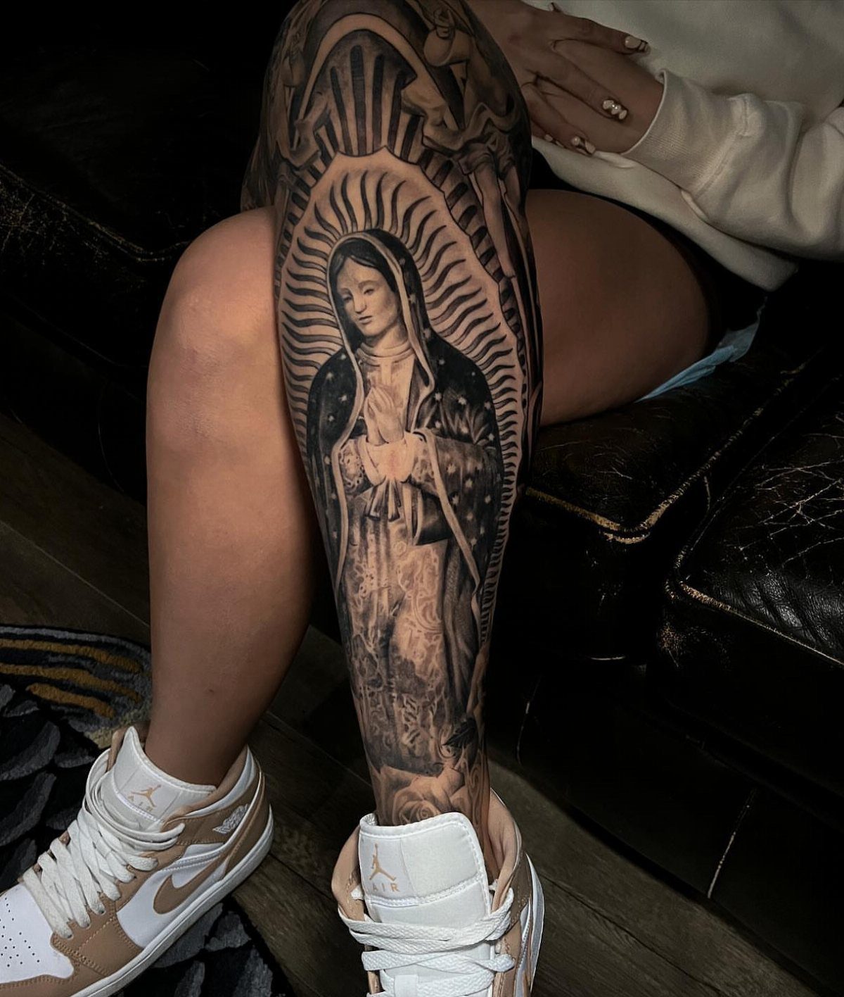 Virgin Mary tattoo on a lower leg with rays of light and halo.