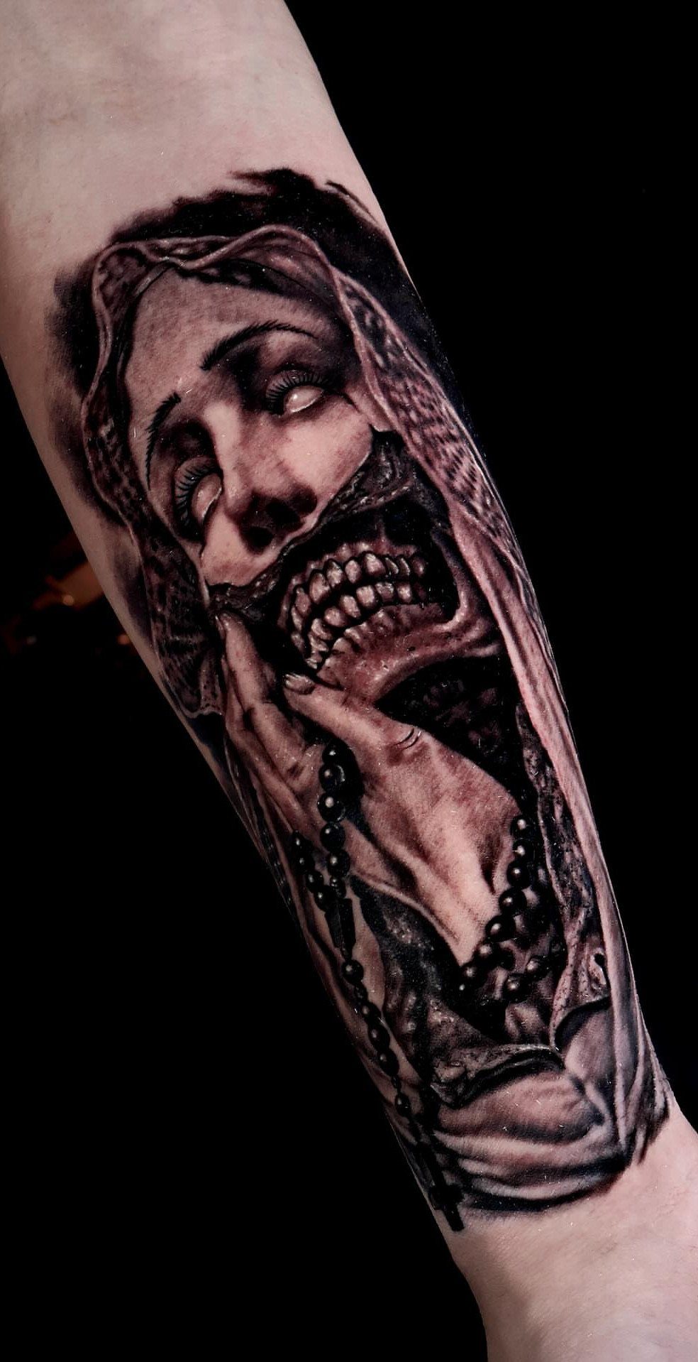 Virgin Mary tattoo with a skeletal jaw and rosary on a forearm
