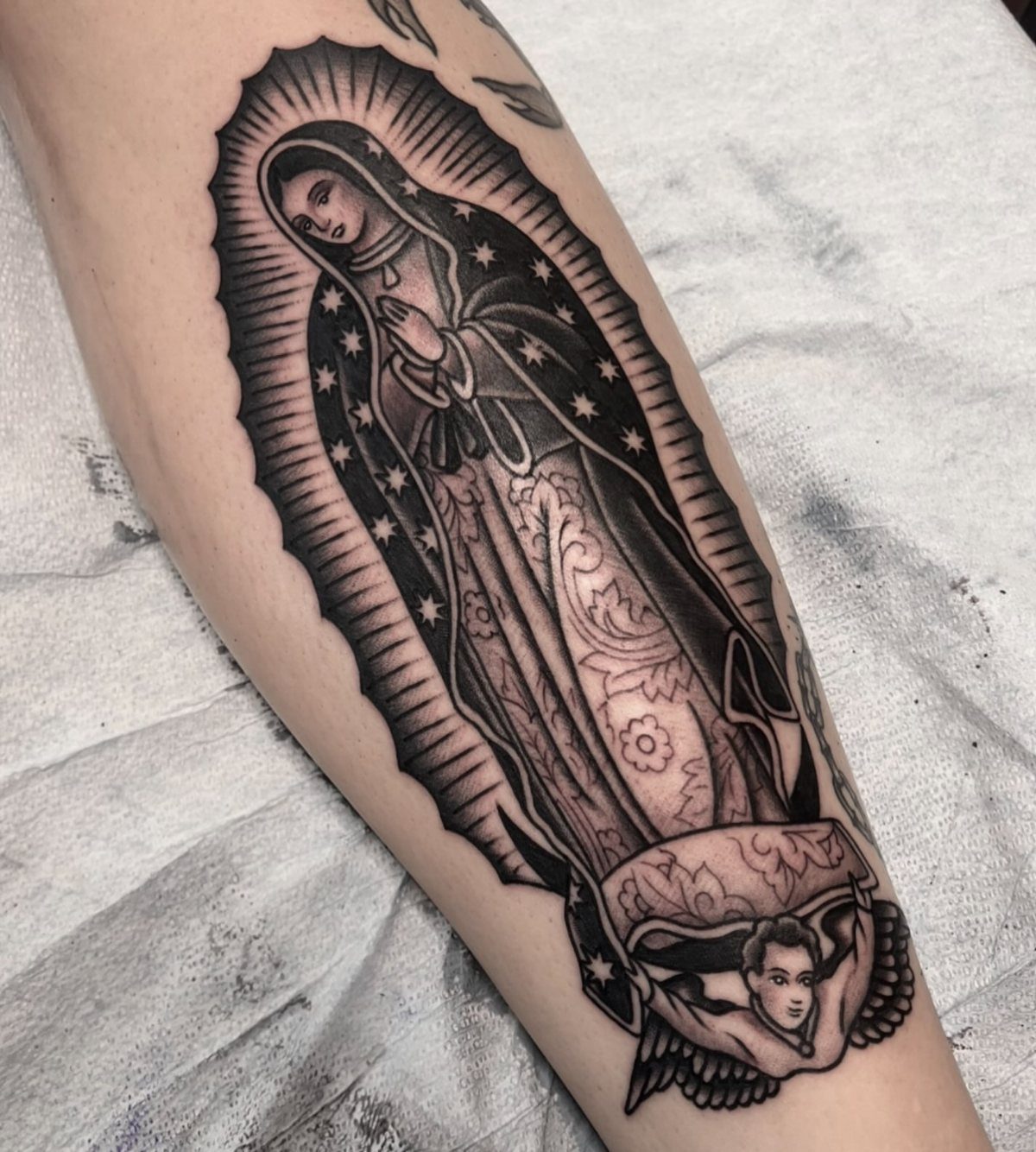 Virgin Mary tattoo with a radiating halo and stars on a person's arm