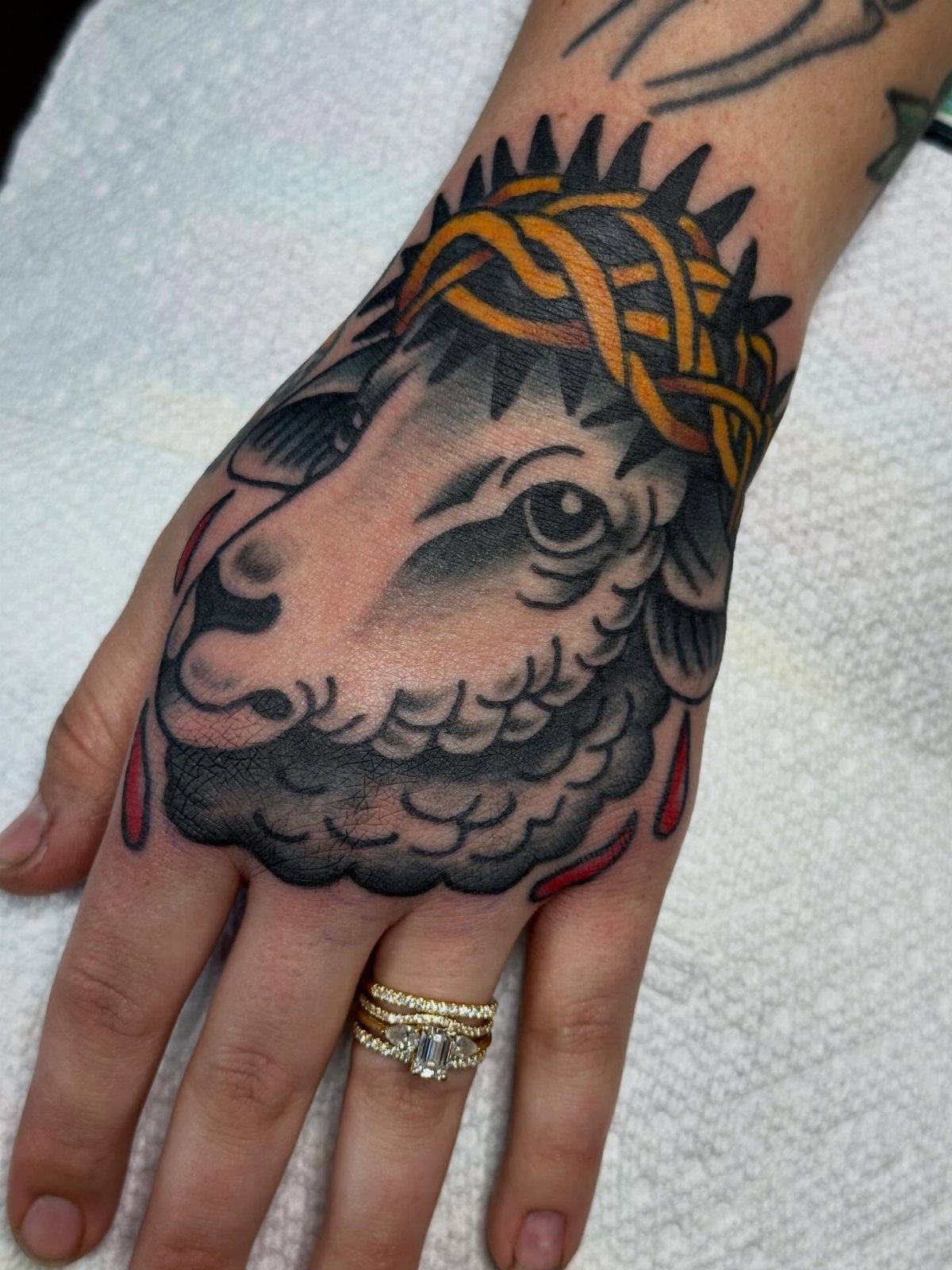 Lamb head tattoo with a crown of thorns on a person's hand